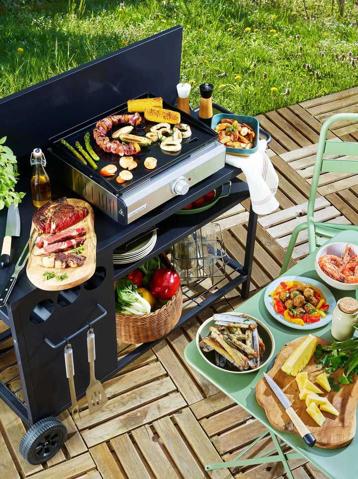 Barbecue avec grillades, légumes, et fruits sur une terrasse en bois.