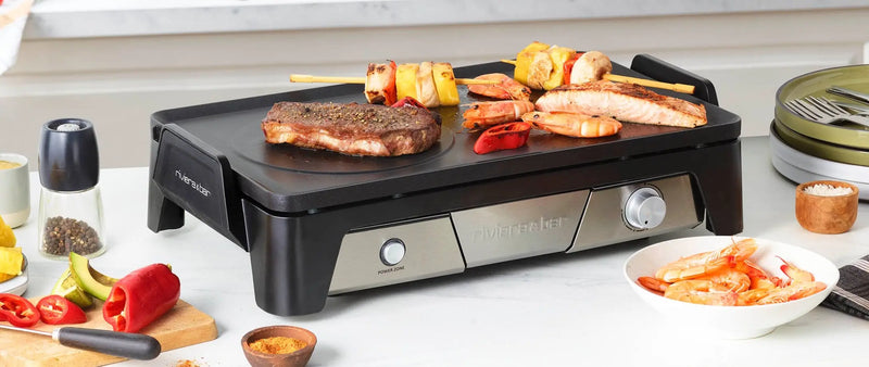 Plancha d’intérieur riviera&bar avec viandes et légumes grillés posée sur table conviviale