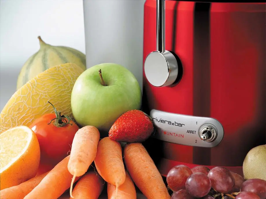Presse-agrumes rouge avec fruits et légumes.
