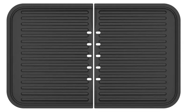 Un tapis de séchage en silicone noir, rectangulaire vu du dessus, avec des stries parallèles et un pli central. Inspiré du plancha-gril Combiné de riviera&bar, il comporte deux sections égales aux angles arrondis.