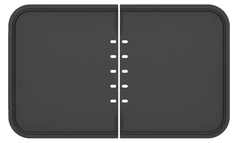 Le plancha-gril riviera&bar Combiné est un appareil rectangulaire noir avec des coins arrondis et une fente centrale avec des petits trous ovales pour un contrôle précis de la cuisson.