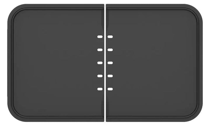 Le plancha-gril riviera&bar Combiné est un appareil rectangulaire noir avec des coins arrondis et une fente centrale avec des petits trous ovales pour un contrôle précis de la cuisson.