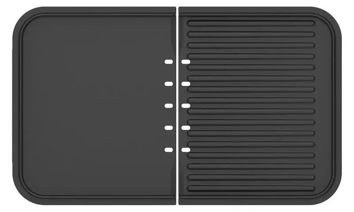 Un tapis de séchage en silicone noir de riviera&bar, conçu pour le plancha-gril Combiné : plat avec un bord surélevé à gauche, strié à droite - idéal pour les outils de cuisine après avoir utilisé votre plancha-gril Combiné.