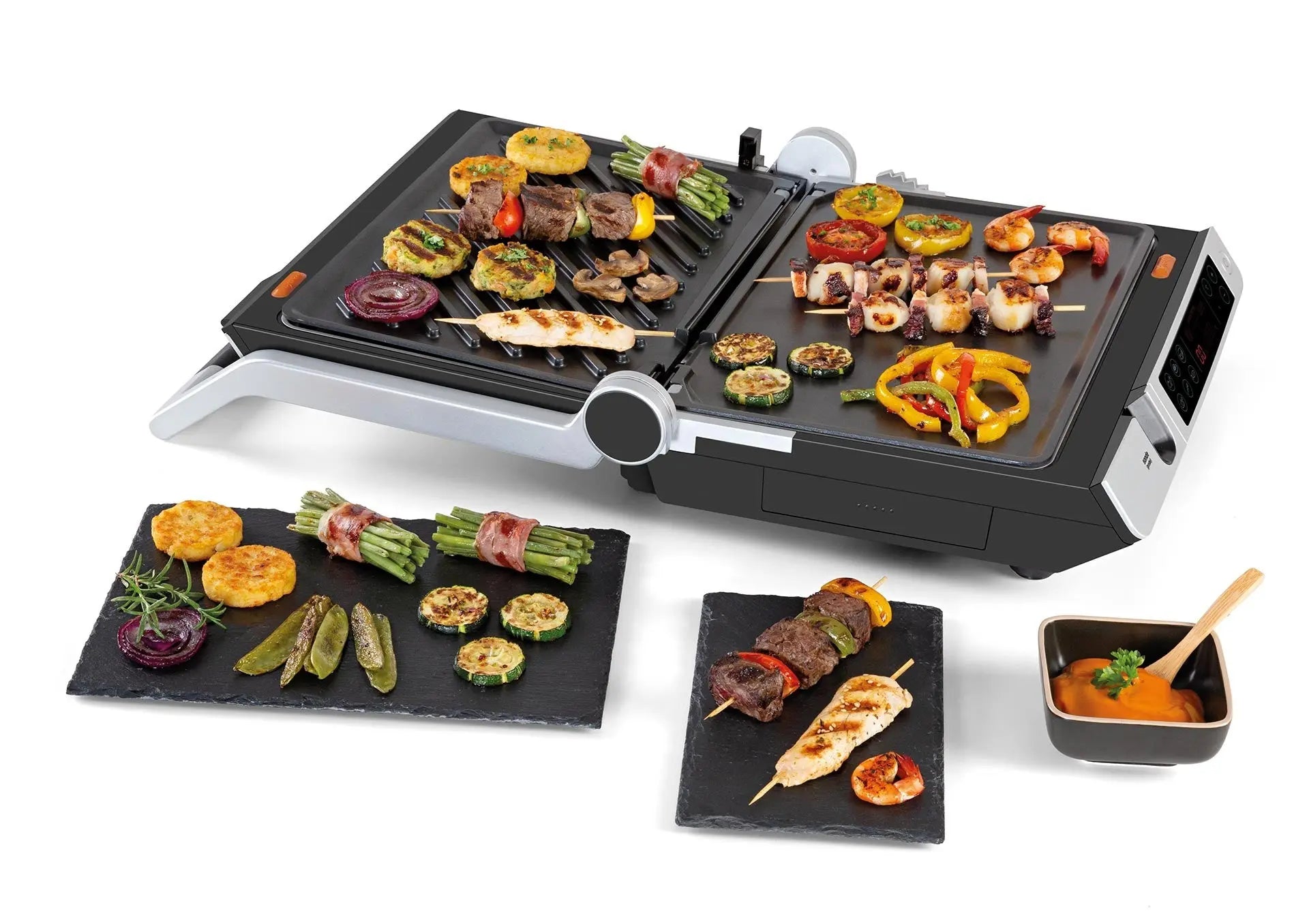 Grill électrique avec brochettes de légumes et de viande, présentées sur des ardoises et une sauce.