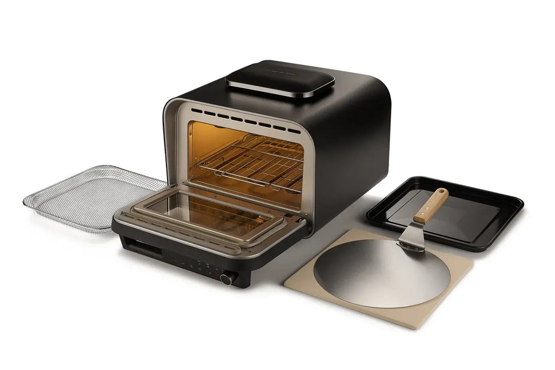 Le riviera&bar Four à pizza électrique 400 degrés est présenté avec sa porte ouverte, exposant des grilles. A proximité se trouvent un panier en filet, une plaque de cuisson, une pelle à pizza avec poignée en bois, une plaque à pizza en métal et une pierre de cuisson - parfaite pour les pizzas italiennes faites maison.