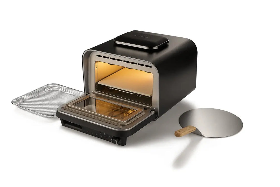 Le four à pizza électrique 400 degrés de riviera&bar, dont la porte avant est ouverte, est présenté à côté d'une plaque à pizza en métal avec un manche en bois et un support en fil de fer - idéal pour préparer une cuisine italienne authentique à la maison.