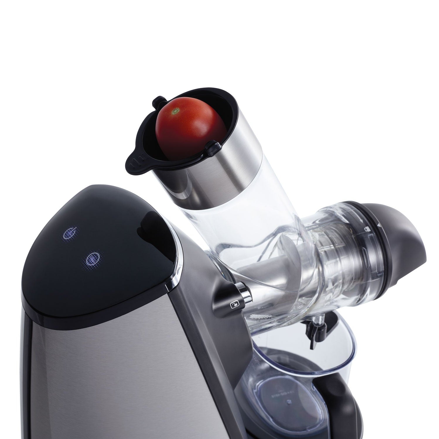Un gros plan de l'Extracteur de jus haute performance riviera&bar montre une tomate entière dans son tube d'alimentation, prête pour l'extraction à froid. L'extracteur de jus est doté d'un design moderne et élégant, avec des touches d'acier inoxydable et de noir.