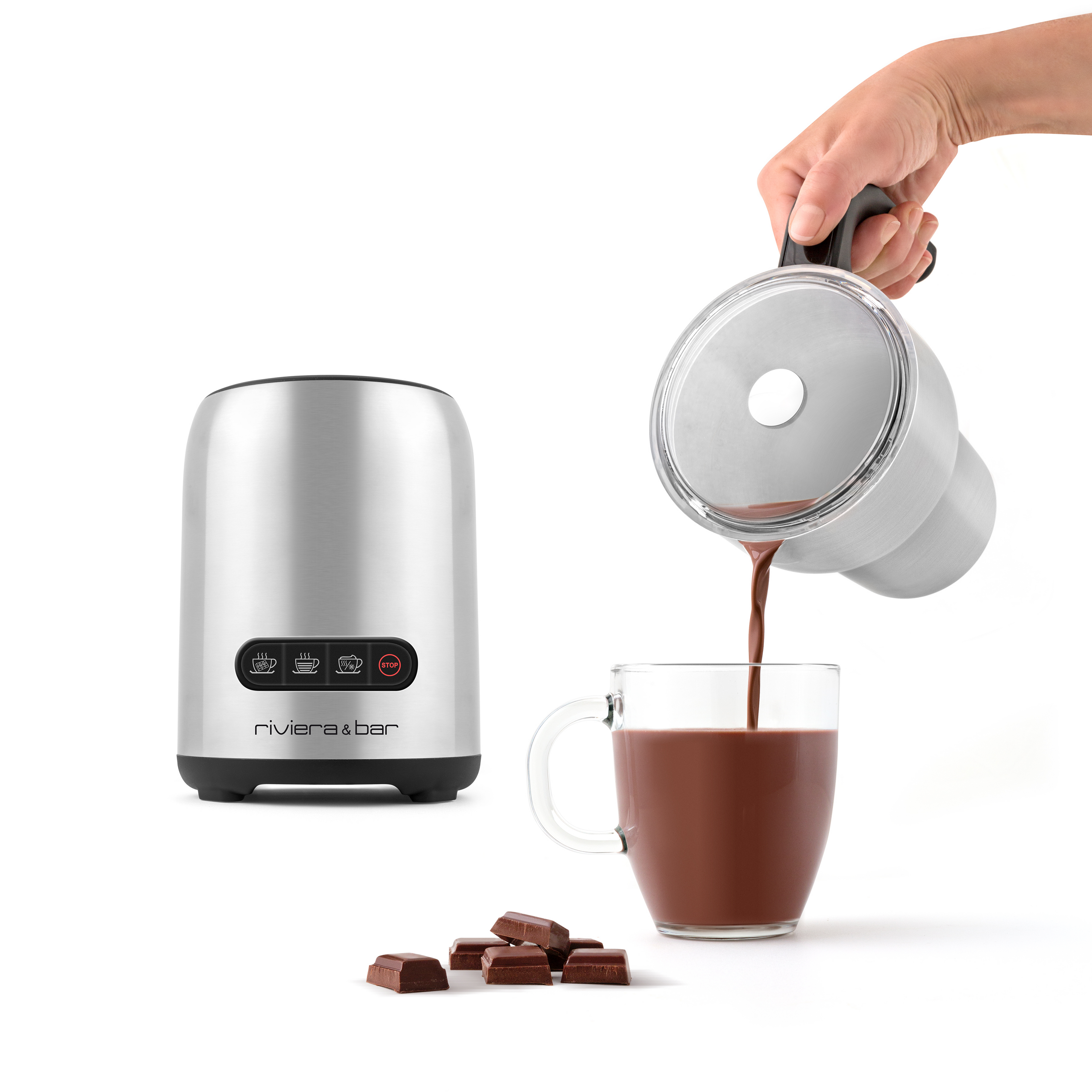 Une main verse du chocolat chaud d'un pichet métallique dans une tasse en verre. A côté se trouve le Chocolatière & Emulsionneur BCL 540 de riviera&bar, avec des morceaux de chocolat sur fond blanc.