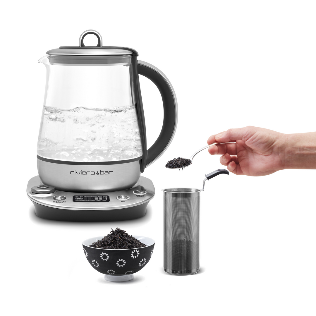 Une main verse des feuilles de thé en vrac dans un infuseur en métal pour une infusion parfaite. A côté, le riviera&bar Théière Sencha Zen (1,2 L) avec de l'eau bouillante et un bol noir contenant des feuilles de thé, le tout sur fond blanc.
