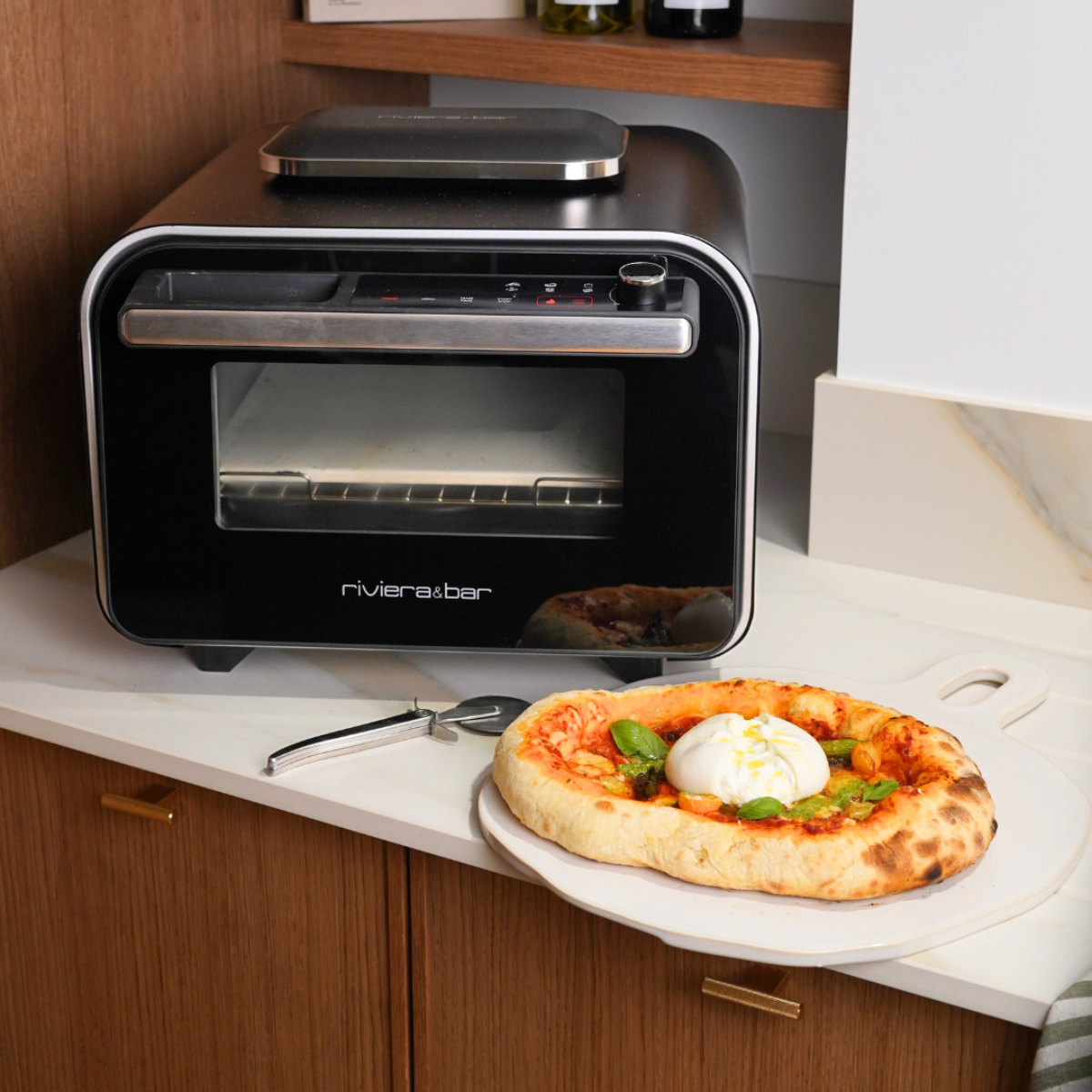 Four à pizza Riviera & Bar noir et inox avec une pizza cuite prête à servir