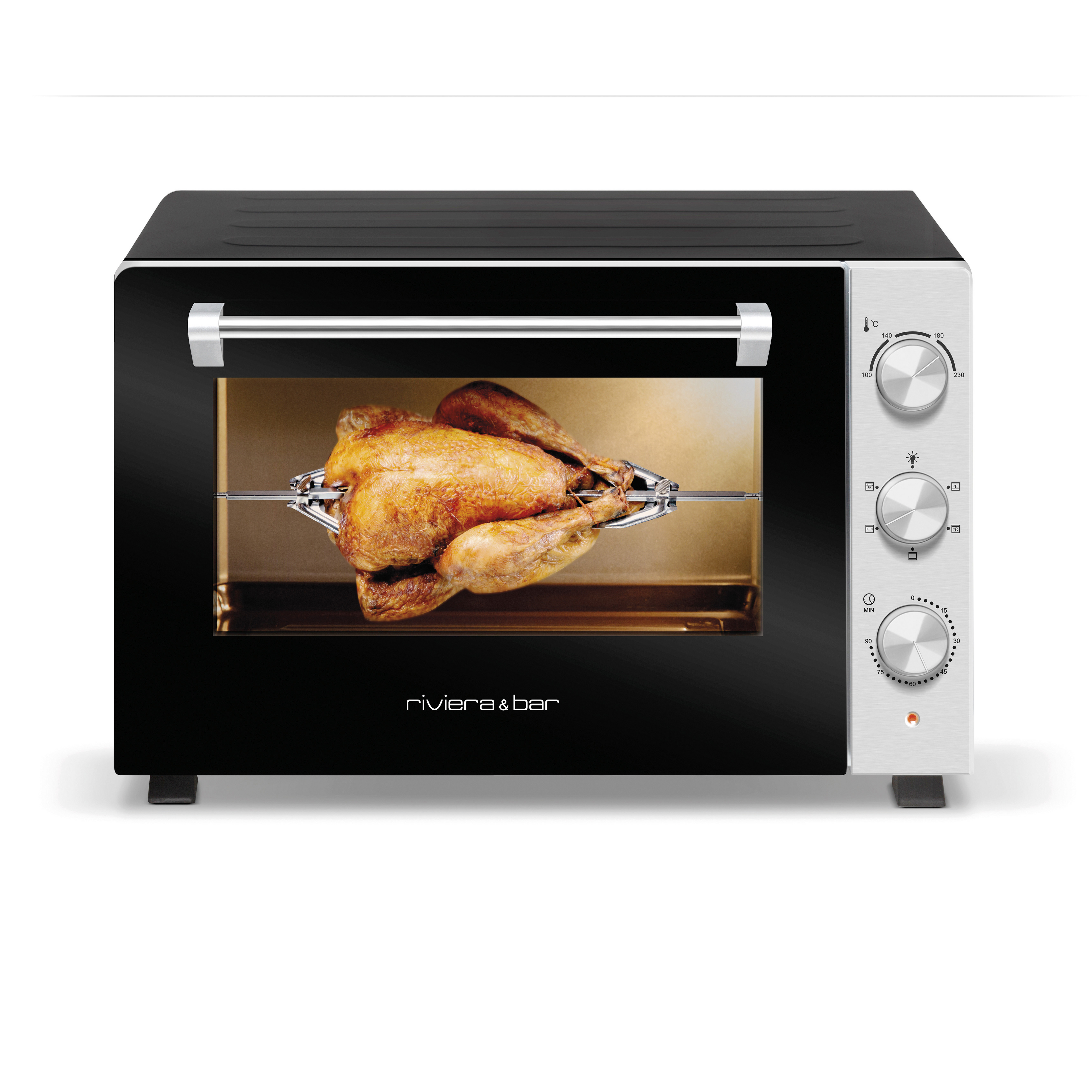 Un poulet entier rôti est cuit sur une tournebroche à l'intérieur d'un four riviera&bar Four posable à parois tempérées 30L, avec un design noir et argenté et des boutons de contrôle sur le côté droit.