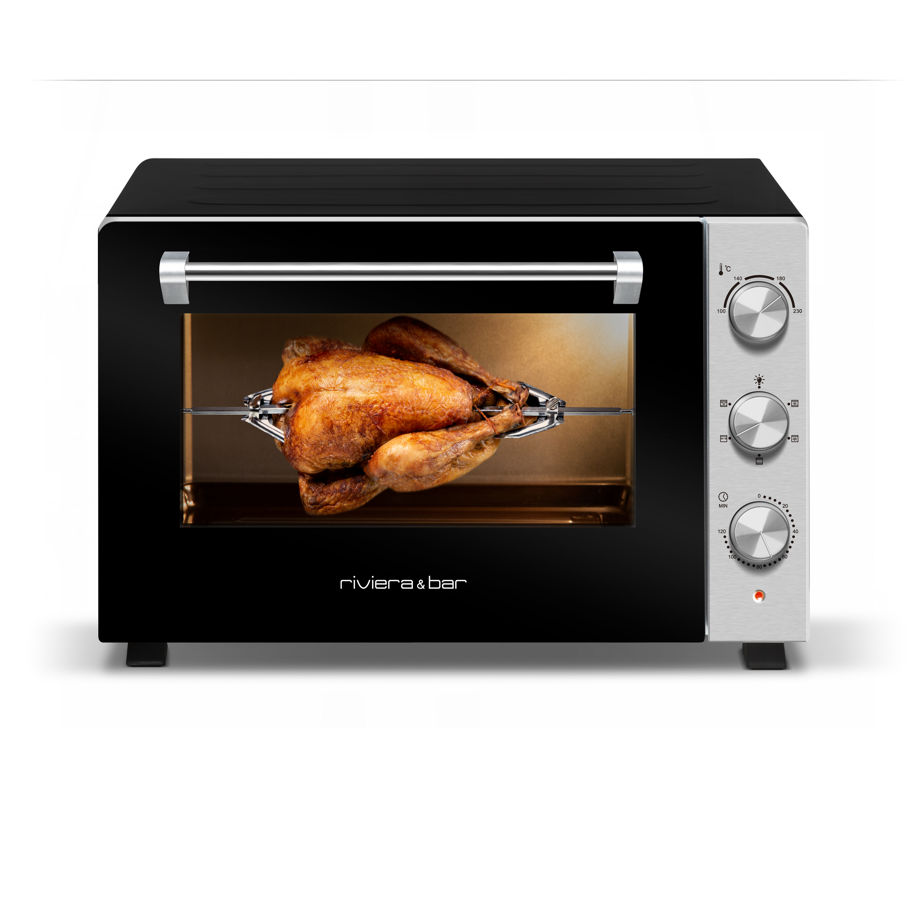 Un poulet entier rôti tourne sur une broche dans un four de comptoir riviera&bar four posable à parois tempérées 60 L avec trois boutons de commande à droite, design noir et argent, idéal pour les grands rassemblements, et le nom de la marque visible sur le devant.