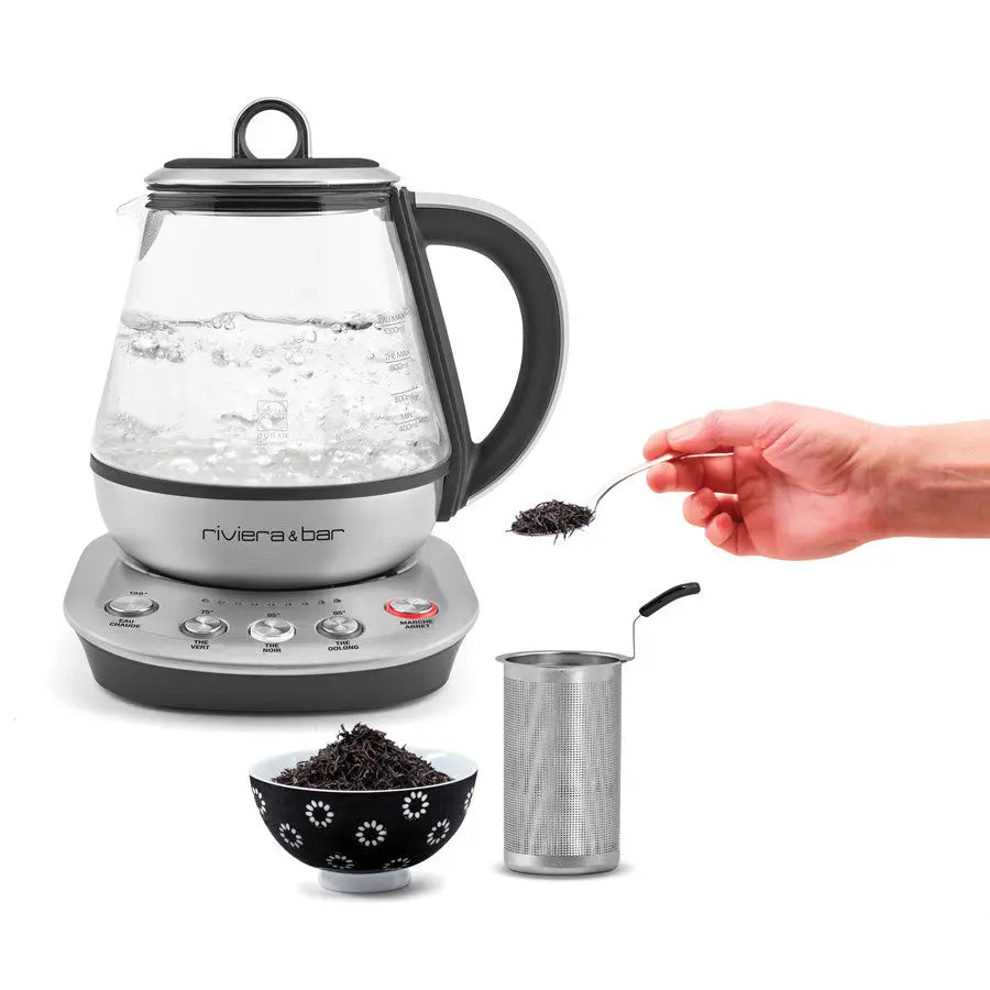 Voici les balises alt : Bouilloire électrique en verre et inox avec sélecteur de température, infuseur à thé en métal, tasse de thé et main tenant une cuillère de thé noir.