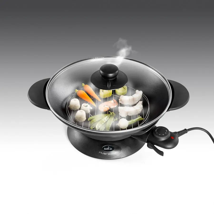 Wok électrique avec couvercle en verre et légumes.
