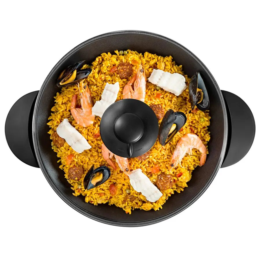 Paella aux fruits de mer dans une poêle noire.
